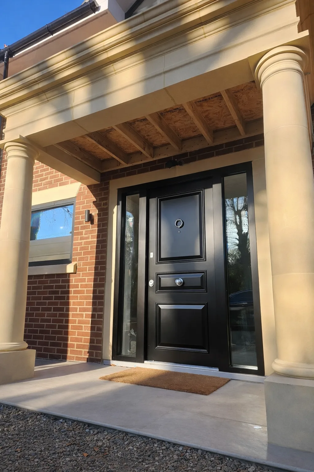Finished black steel security door installed at a residential entrance